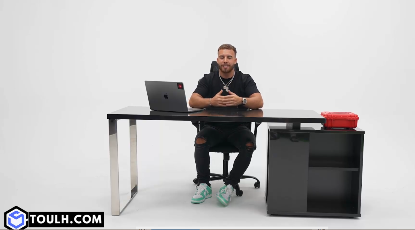 Hombre sentado en escritorio con laptop y material de trading.