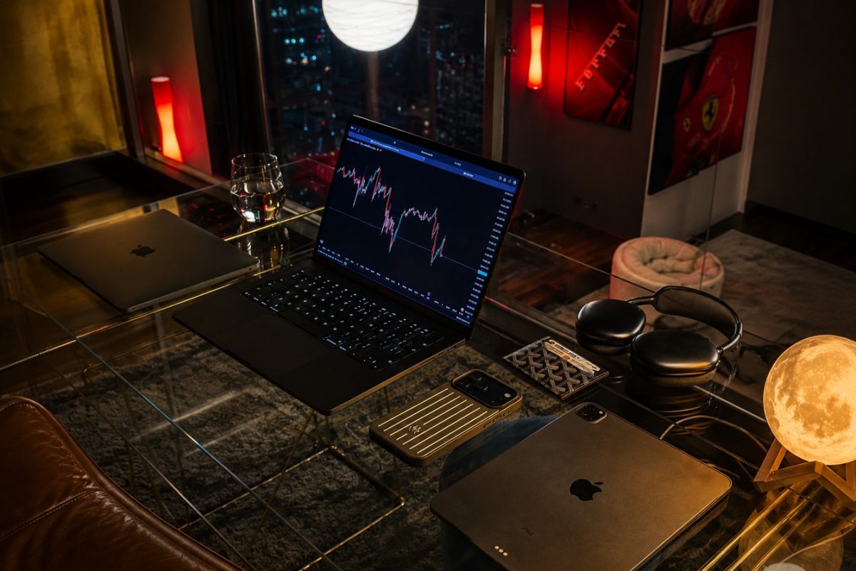 Estación de trading con laptops, gráficos y accesorios en ambiente nocturno.