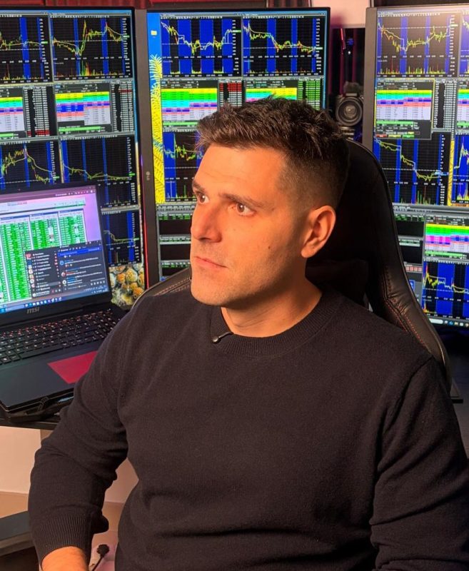 Hombre en oficina de trading con múltiples pantallas de análisis financiero.