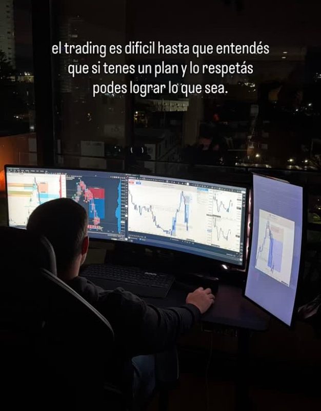 Operador de trading analizando gráficos en múltiples pantallas en la noche.