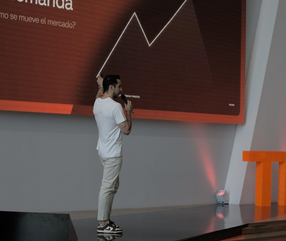 Hombre presentando análisis de mercado en conferencia de trading.