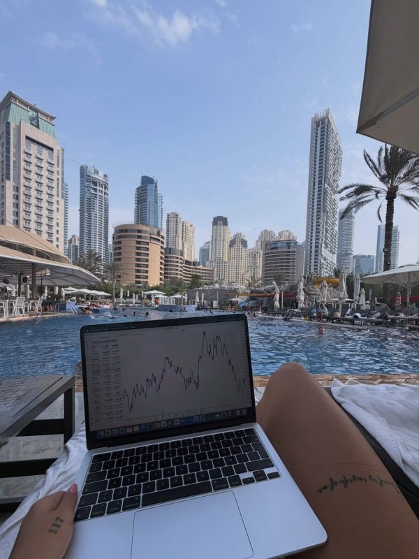 Persona trabajando en trading con vista a la ciudad y piscina.