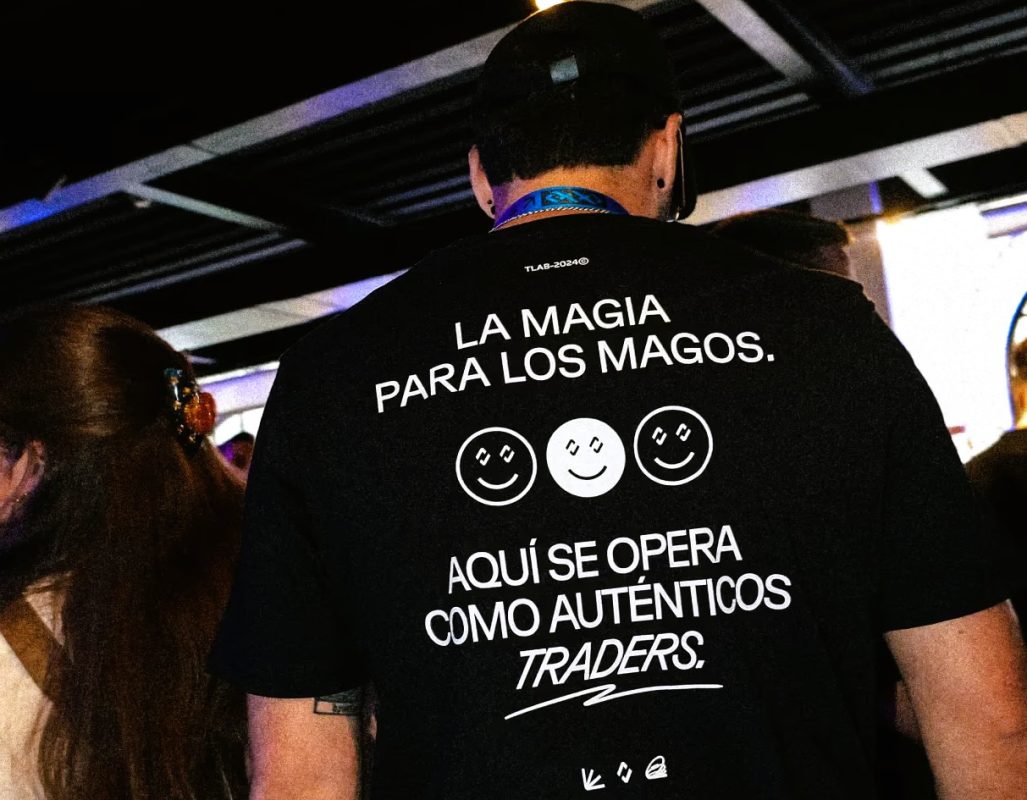 Persona con camiseta que dice 'La magia para los magos' en evento de trading.